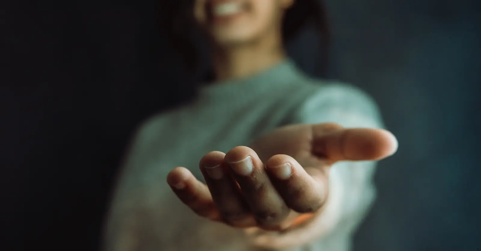 woman smiling and holding outstretched open hand